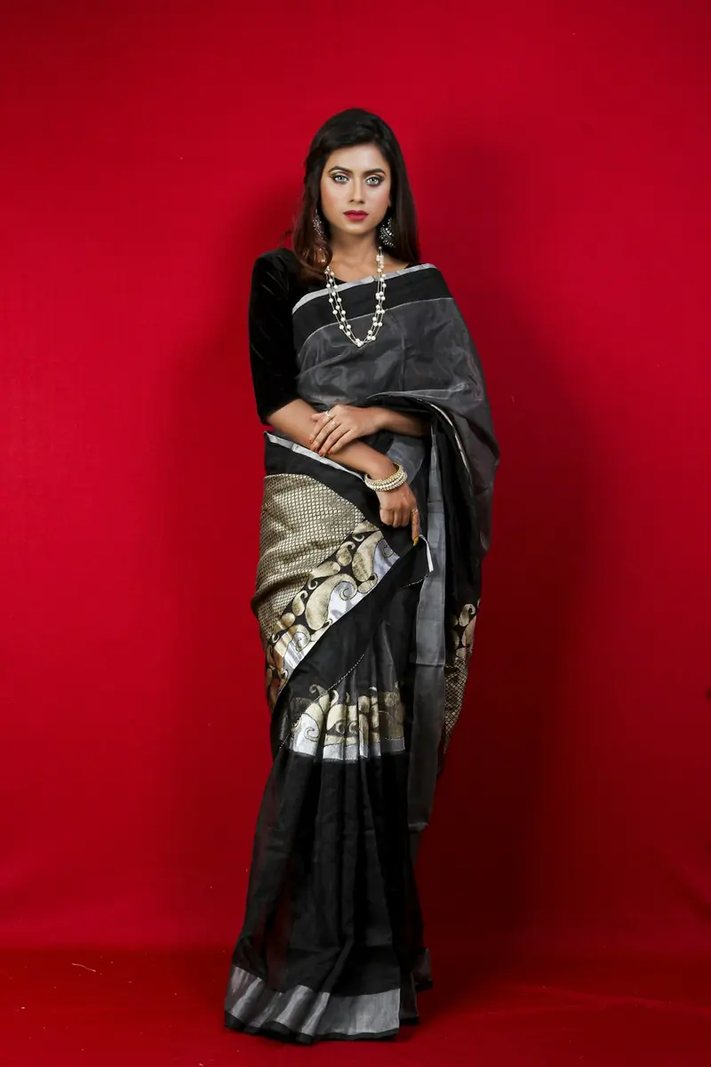 Woman in a black and silver saree standing with her hands resting on the pleats
