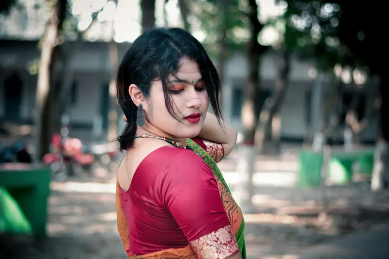 Woman in a pink blouse and green saree looking back over her shoulder